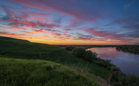 Summer landscape with a river against the backdrop of a colorful sunset sky. An epic evening landscape with fantastic skies.の写真素材