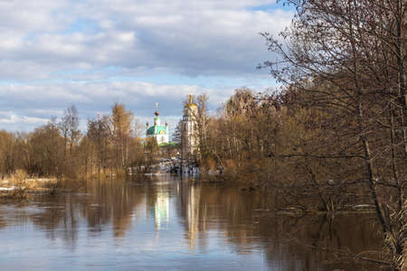 Spring flood. High water. Church on the banks of the river. Rural landscape in early spring. Clouds and trees reflected in the water.の写真素材