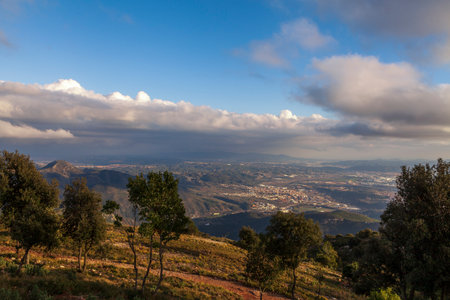 Aerial view of the Montserrat mountains on a beautiful spring day, Catalonia, Spain. Dramatic sky over the mountains. Sunlight falls through the clouds on the ground and mountains.の写真素材