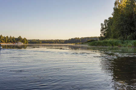 Landscape with a dramatic sky reflected in the river. Early spring, juicy May greens. Bright green...