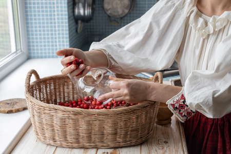 A girl in a folk costume makes tea from herbs and flowers. A woman in the kitchen is preparing her own tea.の写真素材