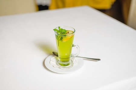 Green mint tea with lemon on white table. Breakfast in empty restaurant.の写真素材