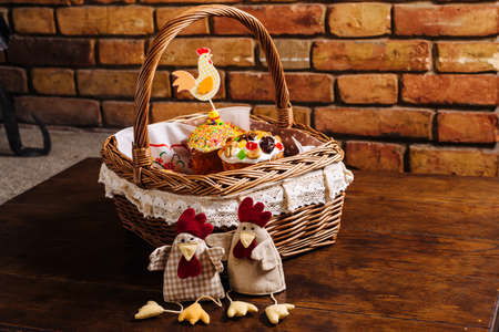 Easter basket with ukrainian easter cake, cookies and Easter eggs on a wooden desk. Easter chicken figuresの写真素材
