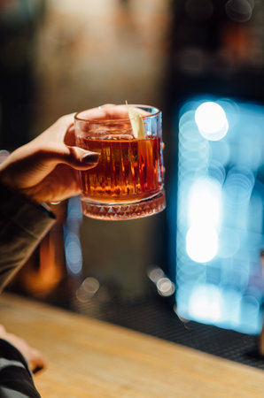 Close-up of female hand holding a glass of whiskey in the barの写真素材