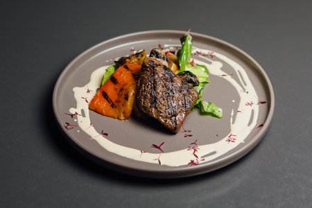 Steak with vegetables on a plate in a restaurant on a black backgroundの写真素材
