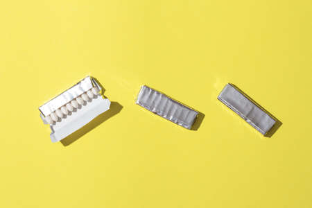 Open package of gum on yellow background.