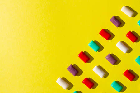 Multi-colored chewing gum on a yellow background.の写真素材