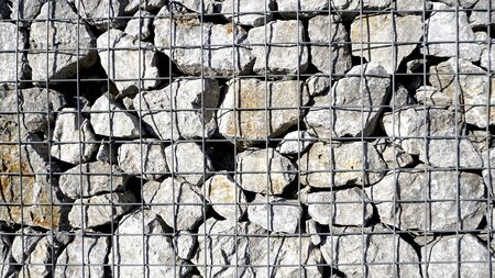 Gabion filled frame with thick stones, Metal stone basket filled with large natural stones texture background for exterior soundproofing acoustic designの写真素材