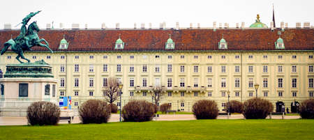 Landscape of Hofburg Imperial Palace building architecture with lots of windows and doors facade in pastel colors with metal statue and grass field foreground Vintage style color in Vienna, Austriaのeditorial素材