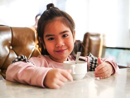 The face of the child with feeling happy with her breakfast milk cup