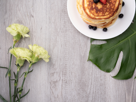 The dish of pancake with strawberry on top on the table with white backgroundの写真素材