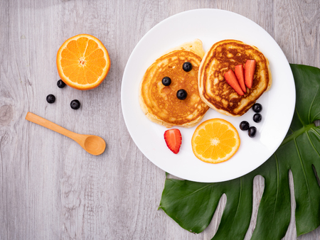 The dish of pancake with strawberry on top on the table with white backgroundの写真素材