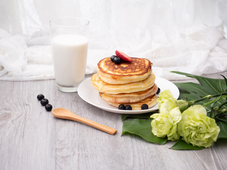 The dish of pancake with strawberry on top on the table with white backgroundの写真素材