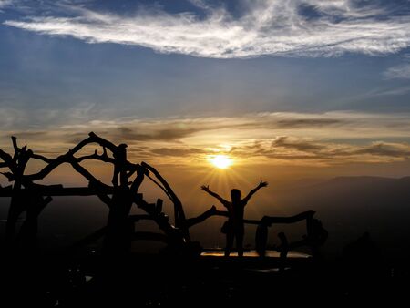 silhouette picture of the woman who was relax on the travel trip in the mountain at the sunset timeの写真素材