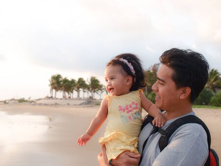 Dad was hold a little daughter in his hug and travel at the beach first timeの写真素材