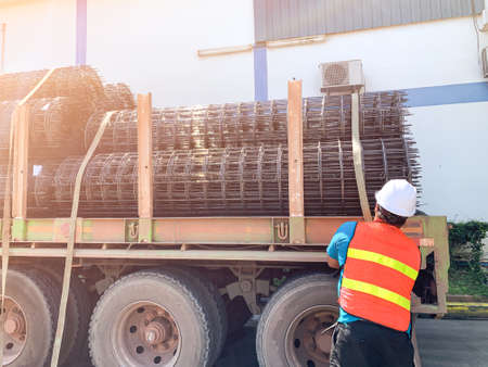 The man was lashing the steel wiremash on the flat bed trailer for distribute to customer
