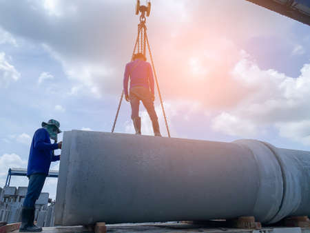 worker were loading the concrete culvert pipe on the trailer floor with yellow lightの写真素材
