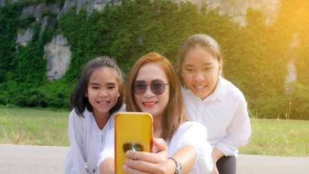 Mom and 2 doughters are happy to taking the photo in the travelling trip with yellow light backgroundの写真素材