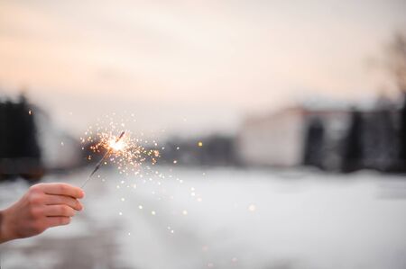 Beautiful sparklers in the hands of a girl on a city background, holiday and Christmas and New Year...