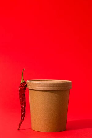 Spicy soup to go in a craft container with red pepper on  redの写真素材
