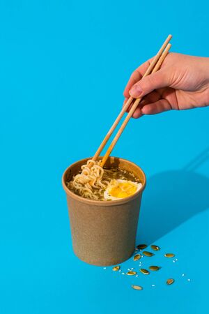 Noodle soup with egg in a craft container on  blueの写真素材