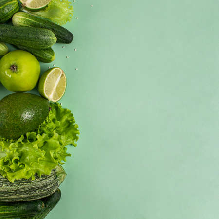 Composition from organic green raw vegetables and fruits: zucchini, cucumber. avacado, apple, lime on a green background. Healthy lifestyle. Balanced diet.の写真素材