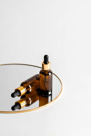 Two glass brown serum bottles with a pipette for skin care are on the mirror. Reflections. The concept of health and beauty. minimalism, copy spaceの写真素材
