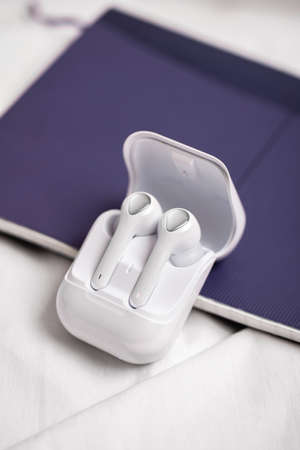 Wireless headphones inside of the box on a white background. Close up view. Using mobile devices....