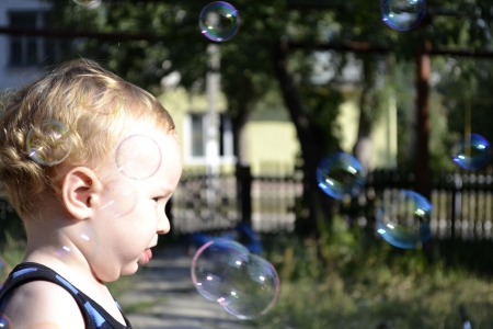 little blond boy watches the flight of bubblesの写真素材