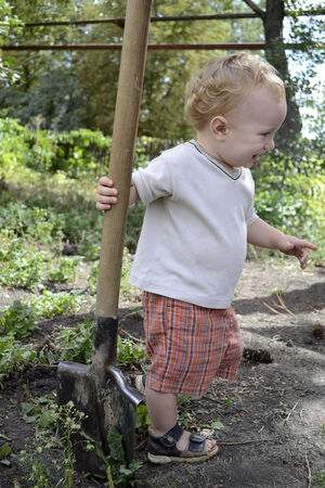 one year old blond kid with a big shovelの写真素材
