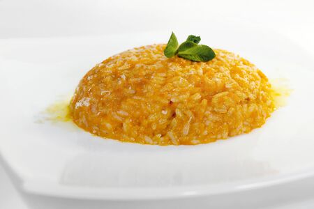 Rice prepared with pumpkin, gorgonzola cheese and chili. Garnished with a mint leaf.の写真素材