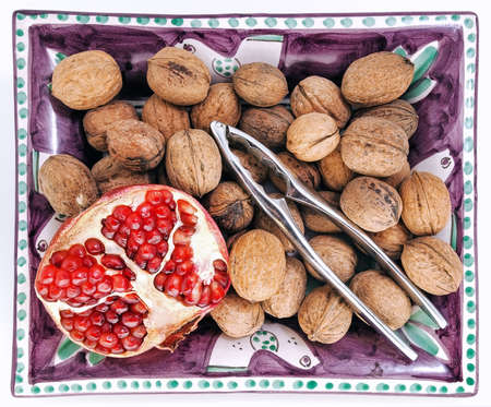 Tray with walnuts, nutcracker and slice of pomegranate, taken from above.