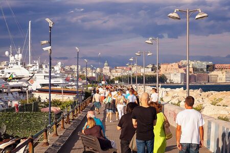Naples, Italy - August 7, 2016: People walk at sunset on the pier of the marina of Naples, next to the boats and the sea.のeditorial素材