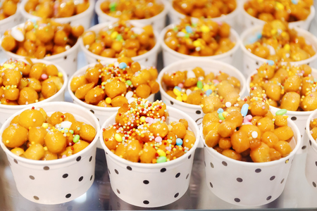Cups filled with Struffoli, typical Neapolitan pastry consisting of many small balls of dough (realized on paper with flour, eggs, lard, sugar, anise liqueur), fried in oil and wrapped in warm honey. Decorated with colored sprinkles.の写真素材