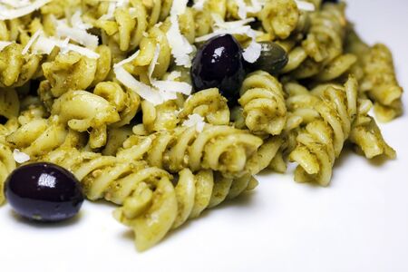 Fusilli topped with pesto sauce, black olives and capers. Meal ready to eatの写真素材