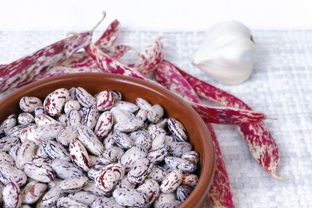 Bowl full of raw beans, on white background. View from above.