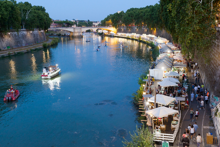 Rome, Italy - July 30, 2017: In the scene the protagonists are the people who stroll down to the river and attend nightclubs. Some boats sail on the river in the night lights.のeditorial素材