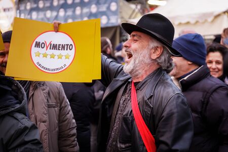 Rome, Italy - March 2, 2018: Five Star Movement demonstration for the conclusion of the election campaign, in Piazza del Popolo. A crowd of supporters gather under the stage. A bearded man rejoices while he shows a flyer with the symbol of the party.のeditorial素材