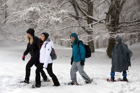 Subiaco, Italy - February 25, 2018: In the middle of winter, four friends hike on the snowy mountain, wearing snowshoes to avoid falling into the deep snow.のeditorial素材
