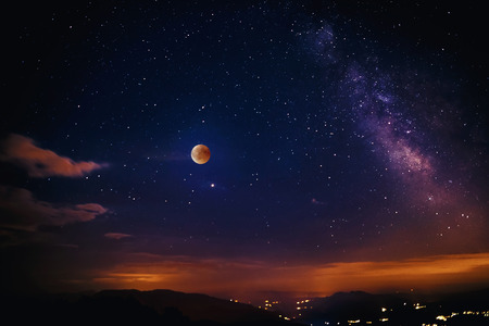 Red moon during the eclipse and in the background the milky way. Composition of multiple images...