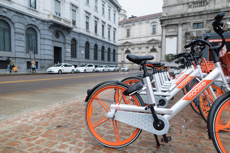 Milan, Italy - October 27, 2018: Piazza della Scala, rental bikes parked in a row on the square. The orange and silver bicycles are from Mobike, a company that guarantees service throughout the city.のeditorial素材