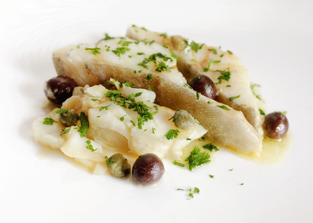 Slices of cod cooked in a pan with a olives and capers, a pinch of parsley, oil and salt.