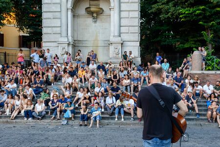 Rome, Italy - June 16, 2019: Piazza Trilussa, a street artist sings and plays the guitar in front of the audience sitting on the steps of the Fontana dell'Acqua Paola.のeditorial素材
