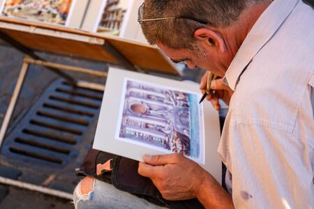 Rome, Italy - June 27, 2019: Street artist paints a watercolor picture in the historic center of the city. He paints a drawing of the Trevi fountain with a brush.のeditorial素材