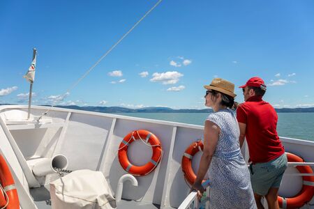 Castiglione del Lago (PG), Italy - July 14, 2019: A man and a woman sail on the bow of the boat that will take them to the Isola Maggiore, on Lake Ttrasimeno.のeditorial素材