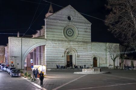 Assisi, Italy - December 7, 2019: The Basilica of Santa Chiara, white and pink front facade with main entrance and square in front. Night view of the church from 1265.のeditorial素材