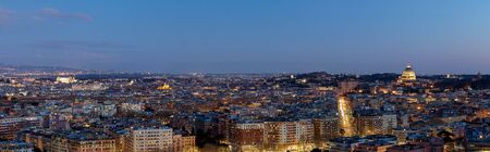 Panoramic view of the city of Rome, Italy, with the major buildings of the capital. St. Peter's Basilica, Castel St. Angelo, the Vittoriano and the Colosseum. Blue hour and night lights.の写真素材