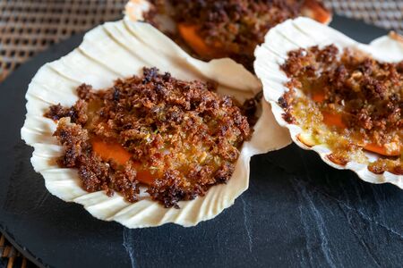 Scallops, au gratin with breadcrumbs, spices and herbs, cooked in the oven and ready to eat. Serve...