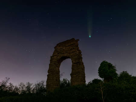 The comet Neowise in the sky of Rome, against the background of the ruins of an ancient Roman aqueduct.の写真素材