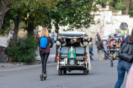 Rome, Italy - October 10, 2020: A woman travels around the city aboard a rented electric scooter.のeditorial素材